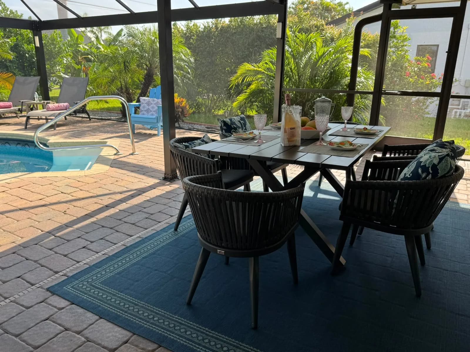 Überdachte Terrasse mit rundem Tisch, vier Stühlen und Blick zum Pool