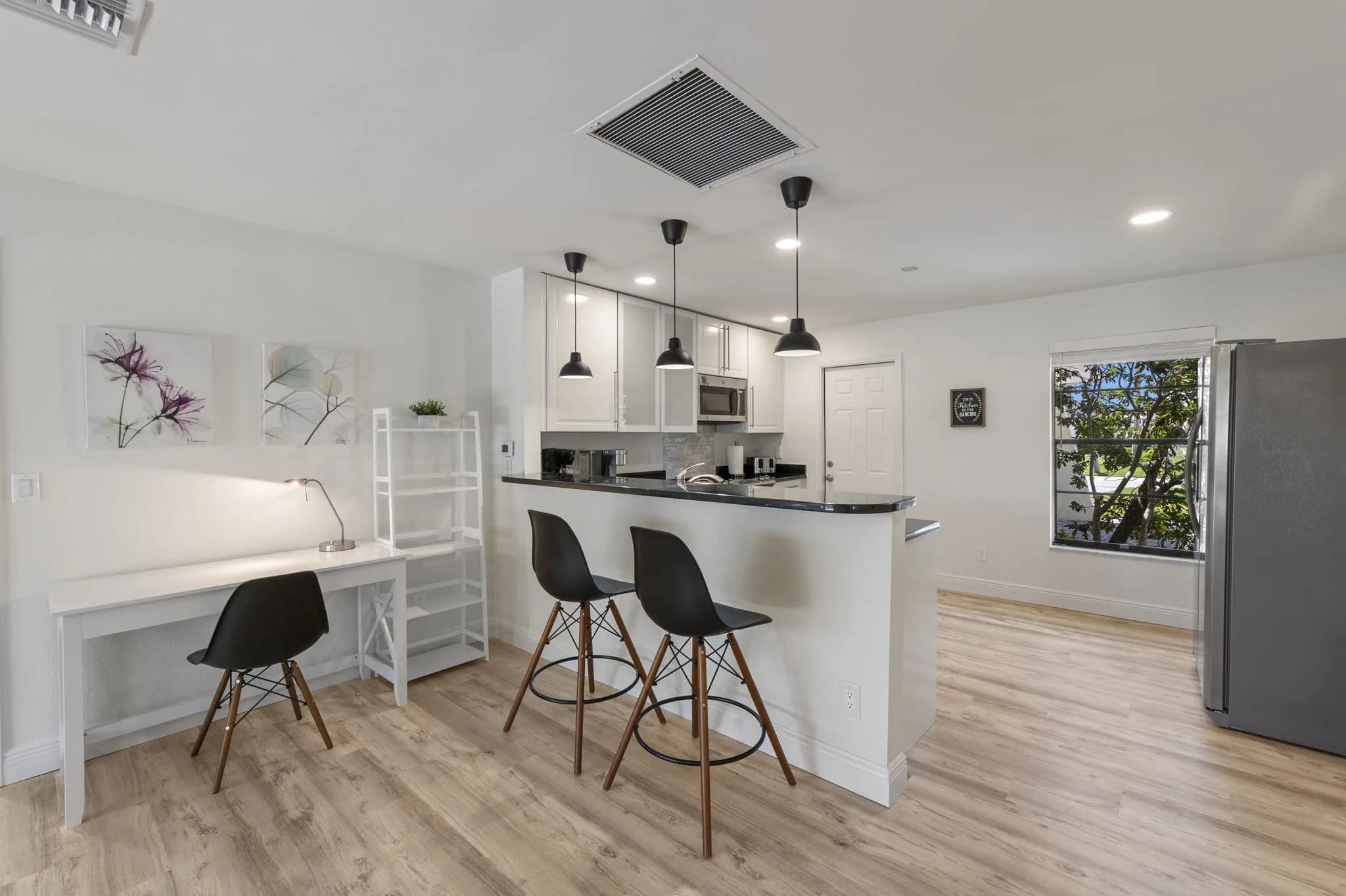 Weiße Küche mit Frühstückstheke, Barhockern und kleinem Arbeitsplatz