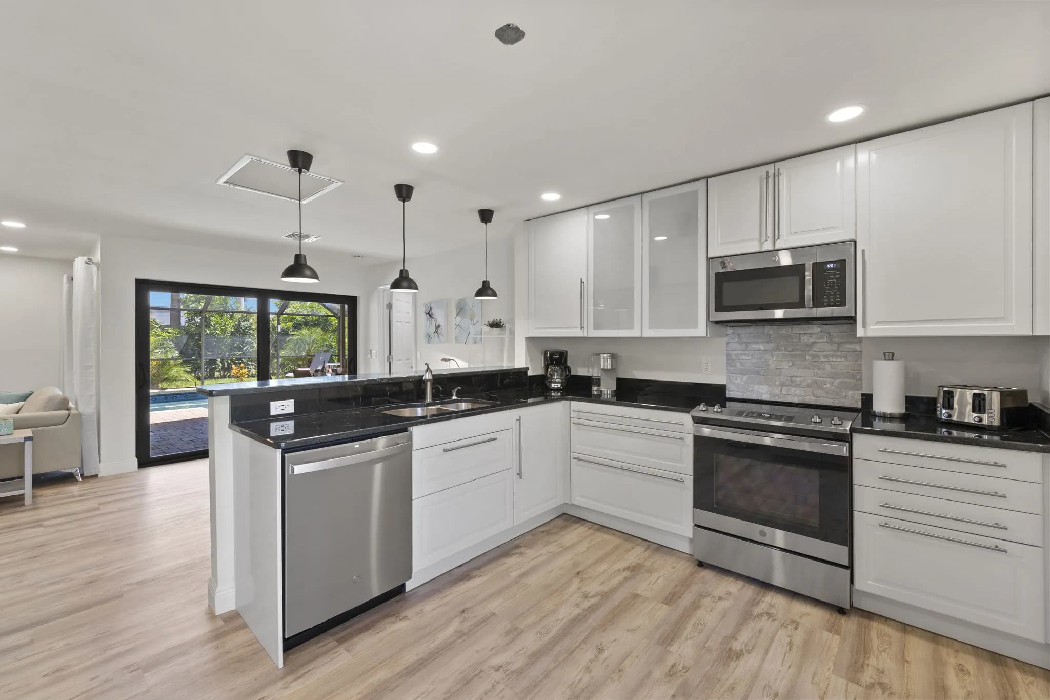 Küche mit weißen Schränken, Edelstahlgeräten und schwarzer Arbeitsplatte